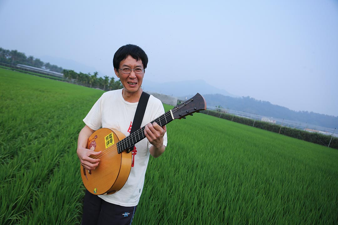 林生祥在高雄美濃家附近的田野演奏樂器。