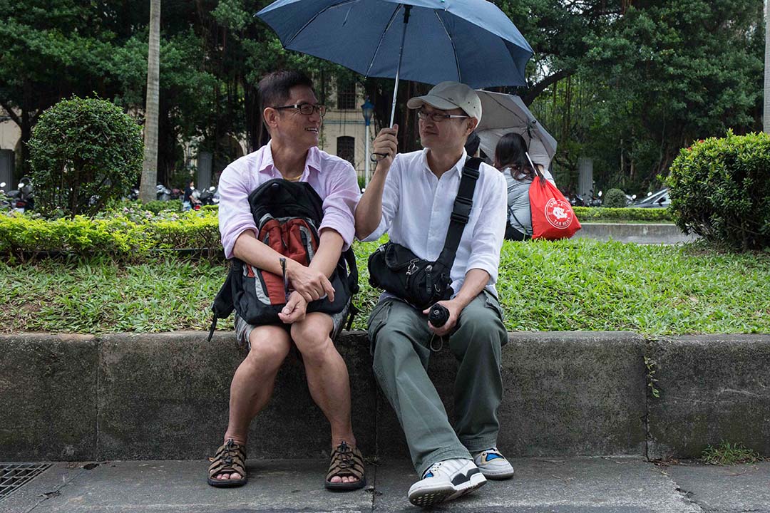 圖為2016年台灣同志遊行,一對同志情侶在路邊休息聊天。