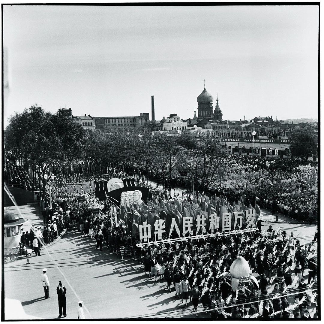 1963年10月1日哈尔滨,国庆阅兵期游行人士高举写着「中国人民共和国万岁」大字的木板,其后是毛泽东、马克思、恩格斯、列宁、史达林的头像。旁边是圣索菲亚大教堂。