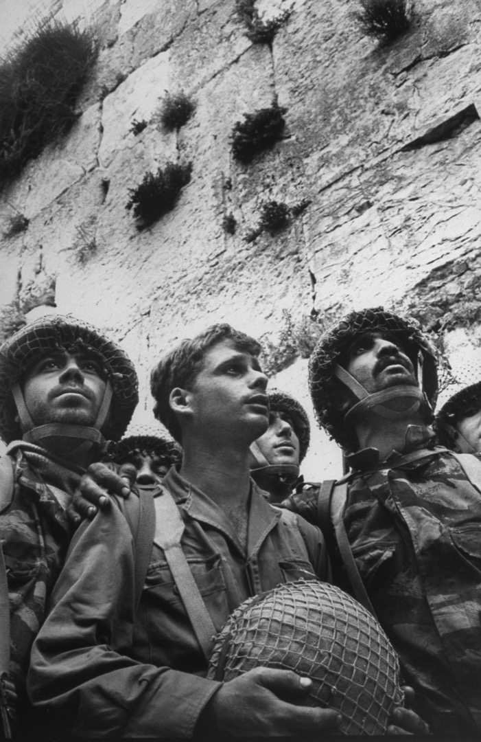1967年6月9日,以色列士兵站在耶路撒冷旧城区的哭墙前,在此之前耶路撒冷归属约旦统治,不容许犹太人到哭墙祷告,哭墙无人哭达19年之久。从“六日战争”以后,以色列士兵在哭墙前祈祷的画面便深深地刻在以色列的国家意识中,耶路撒冷成了狂热的宗教崇拜中心,它作为象征的重要性被强化。