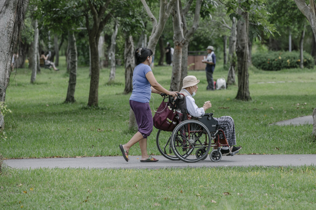 台湾子女对“照顾老人”的想像,恐怕还是“送养老院”这样的图像居多,但多半都会面对“不孝”的骂名,许多子女不堪指责、也不忍心与父母分离,便选择让外籍劳工来家照顾父母。图为台北大安森林公园,外籍看护照顾长者。