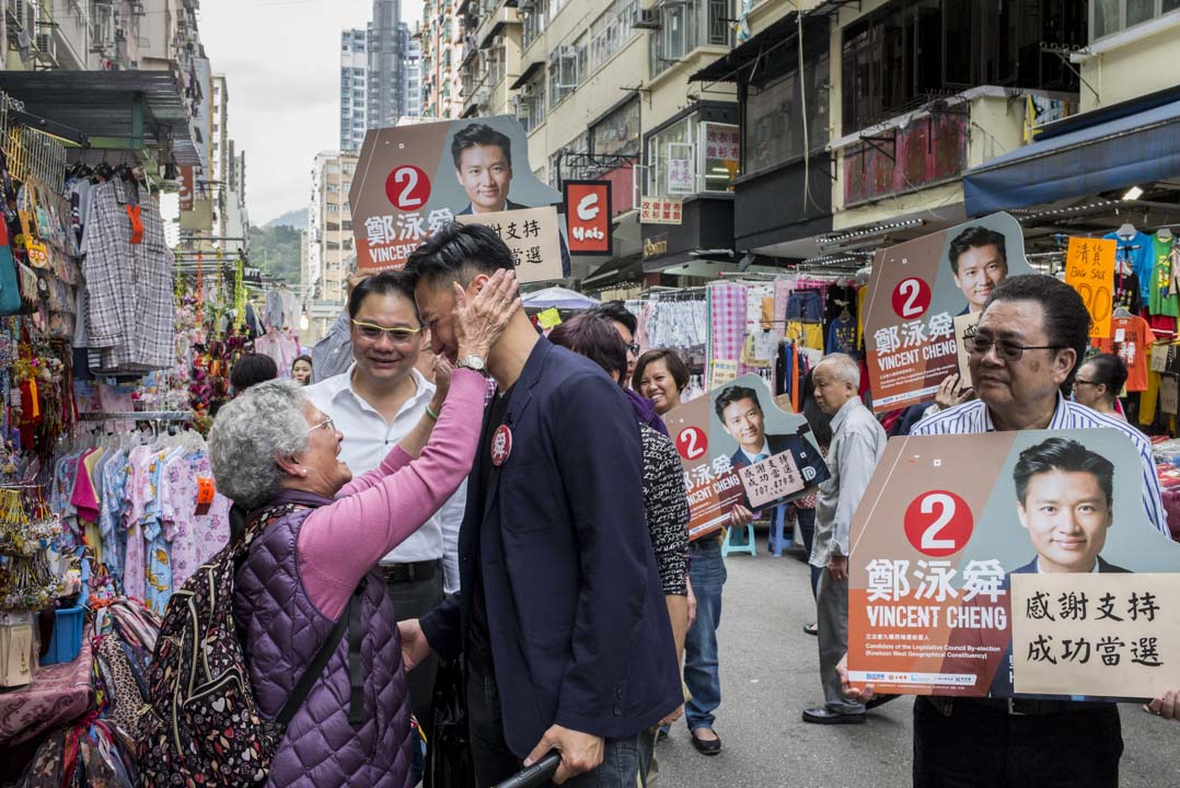 强调地区经验、打“切身民生”议题、以“政治争吵”批评民主派，同时运用新媒体宣传的“郑泳舜模式”，会继续突破民主派在单议席单票制里的防守吗？图为2018年3月13日，郑泳舜在旺角花园街向选民谢票，有支持者向郑表达祝贺。