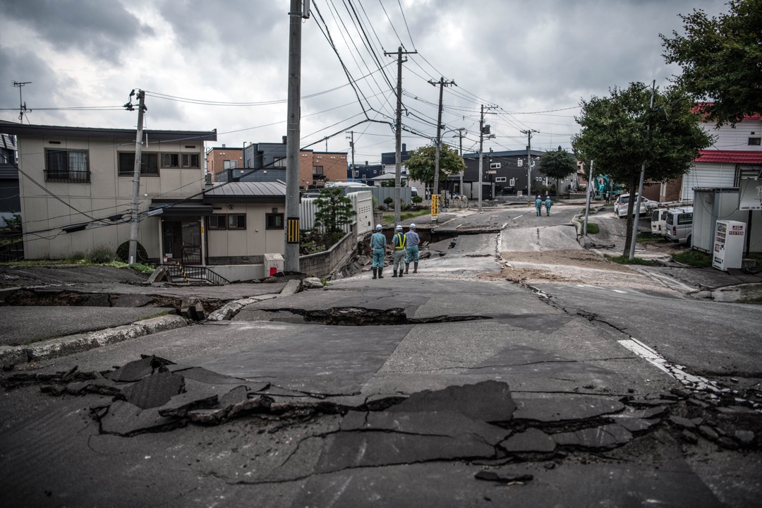 2018年9月7日,日本札幌清田区,道路在地震中严重损毁,数名维修人员在场观察情况。