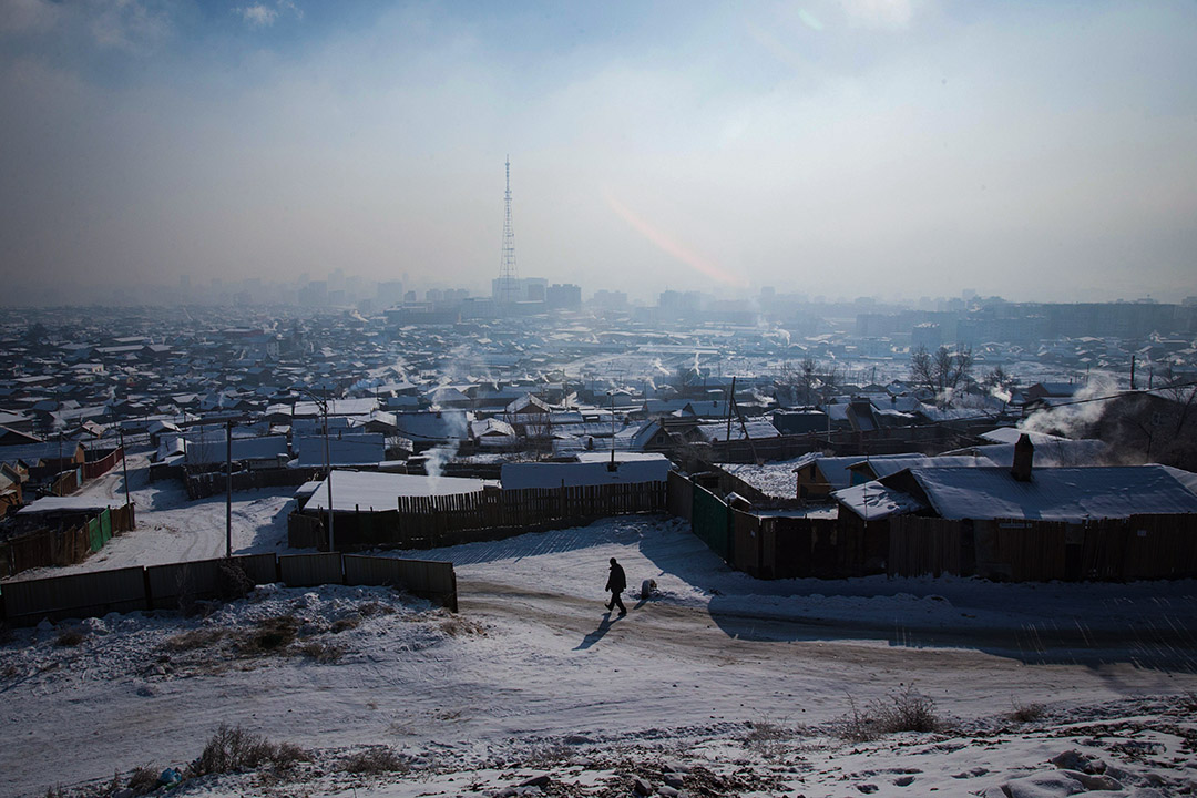 2018年1月21日,在蒙古首都乌兰巴托空气污染严重,一名男子走在冰冷的道路上,烟雾笼罩著城市。