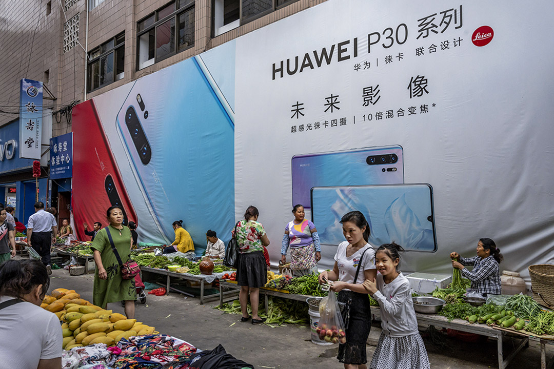 2019年6月1日,雲南省的一個市場,一名婦女與她的女兒在華為智能手機的廣告牌前走過。