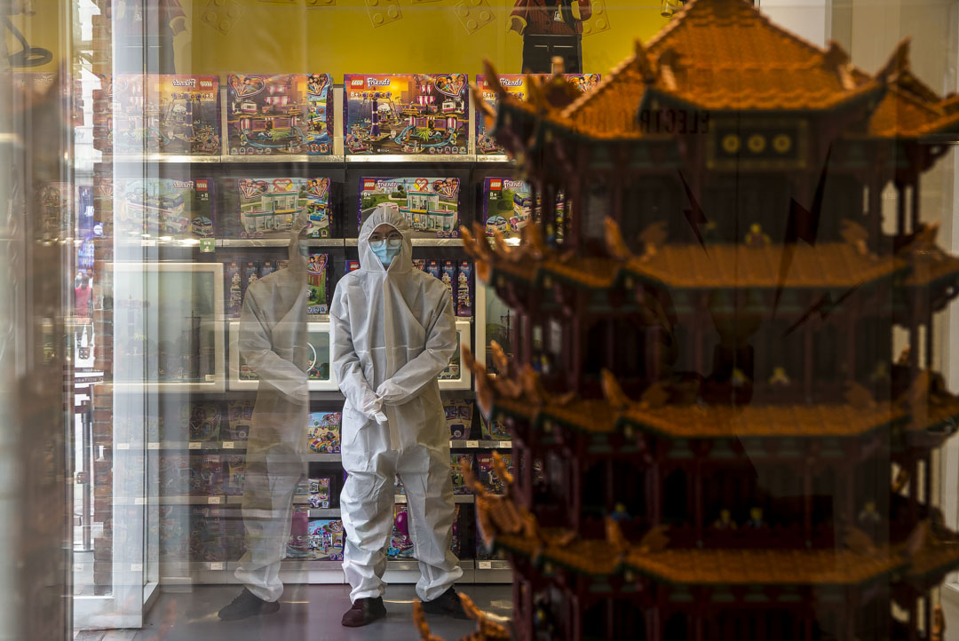 武漢漢街,店員穿防護服守在門口,等著為進門的顧客測量體溫。