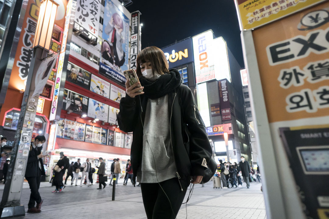 2020年2月13東京,戴著口罩的婦女使用智能手機。
