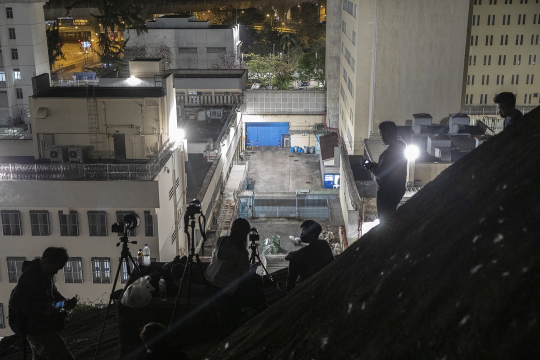 2021年3月2日凌晨,一众摄影记者在山坡上等候拍摄被押解到荔枝角收押所的被告。摄:林振东/端传媒