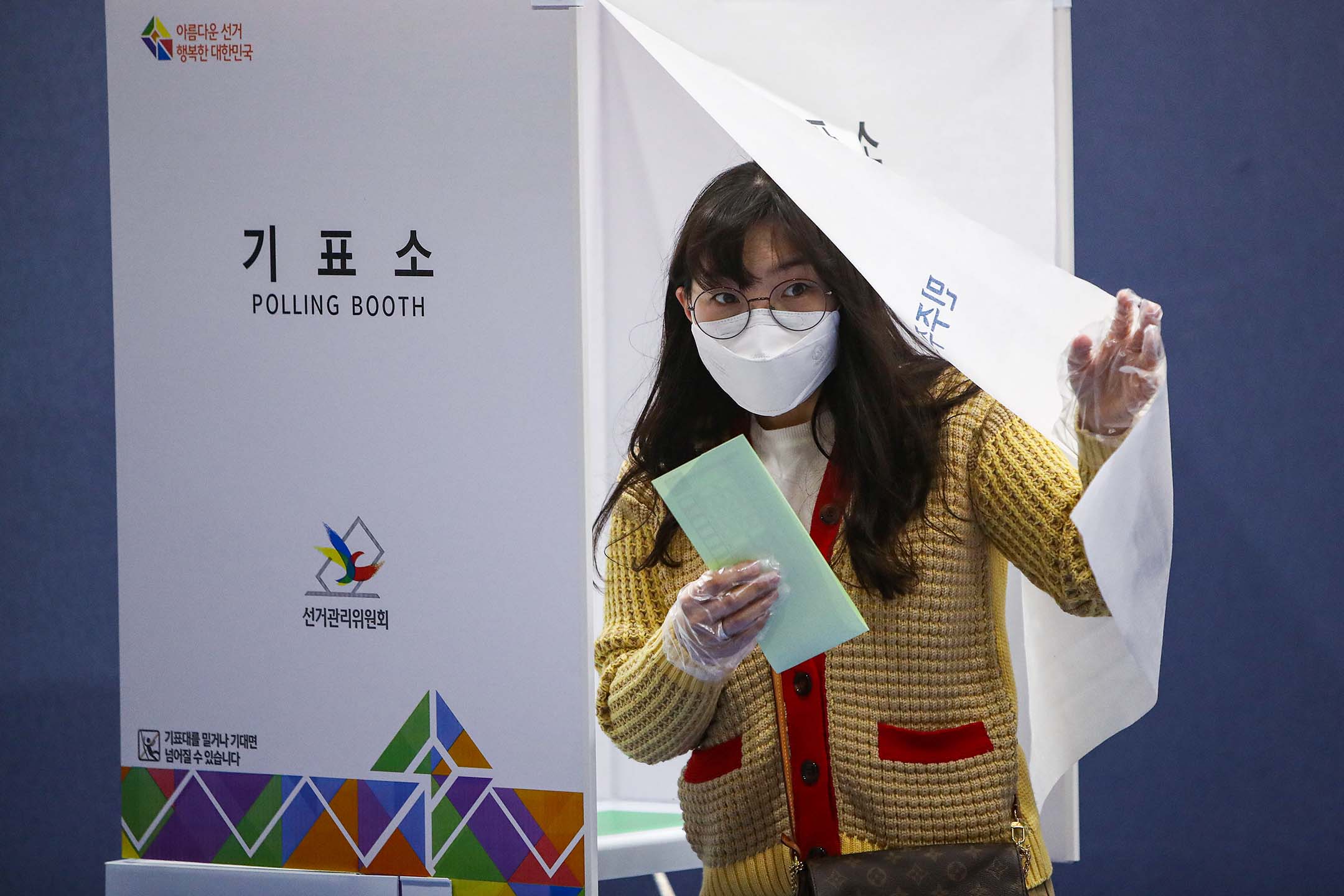 2020年4月15日韩国首尔,一名韩国妇女戴著口罩及手套在议会选举的一个投票站内投票。