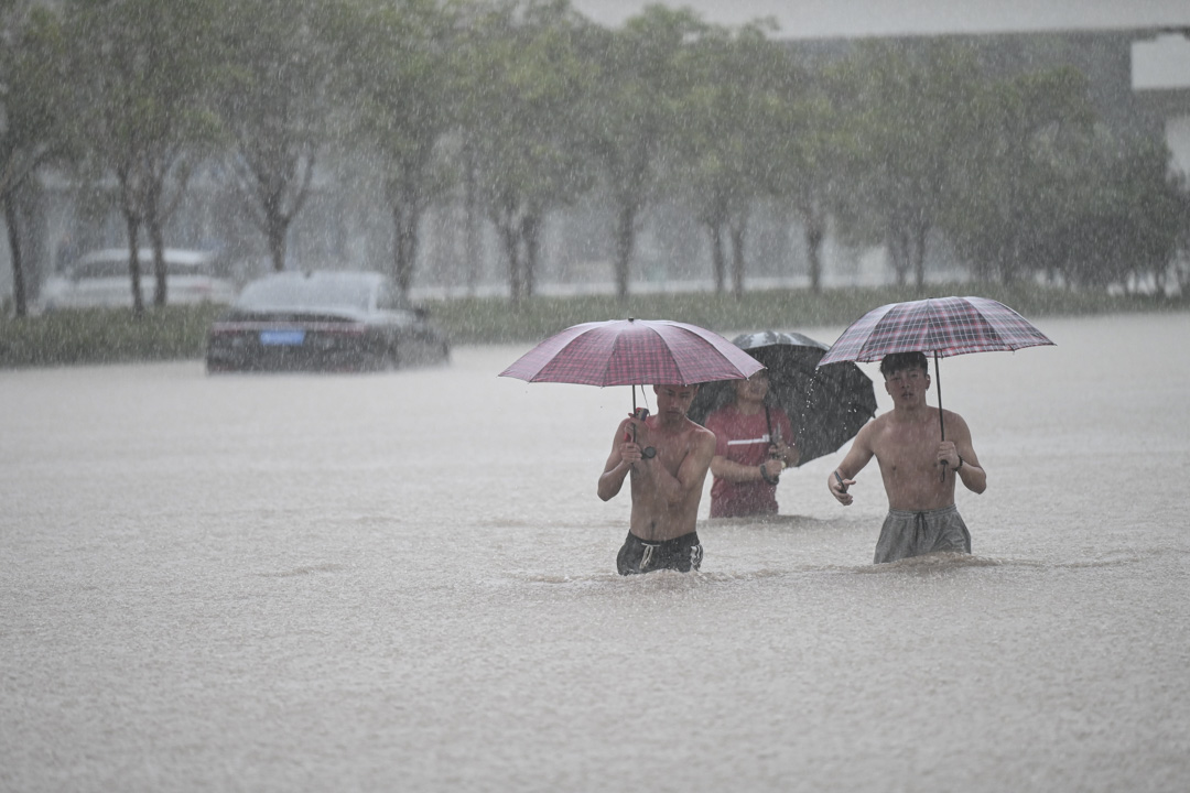 2021年7月20日,河南省鄭州市,人們在鄭州火車站附近的洪水中行走。