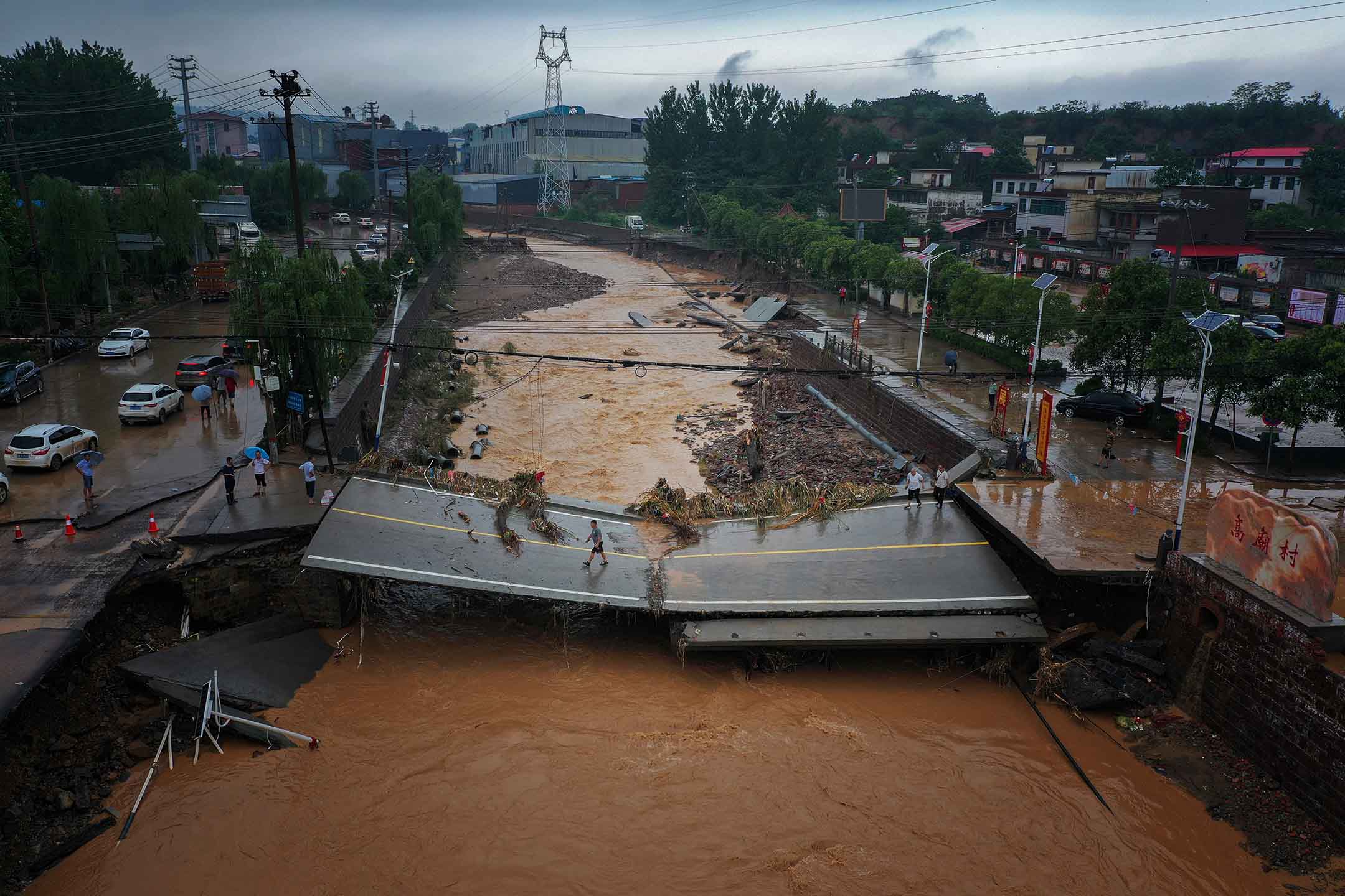 2021年7月21日中国河南省巩义市,暴雨过后,人们走在受损的桥上。