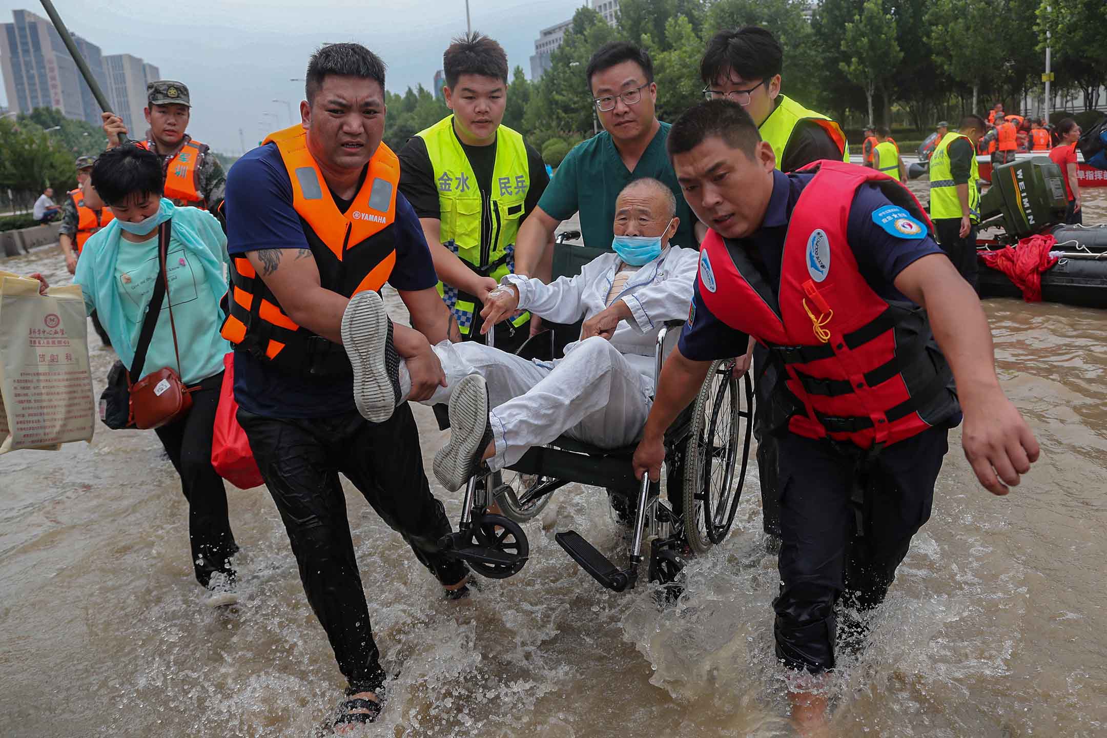 2021年7月22日中国河南省郑州市,救援人员在医院拯救一名坐在轮椅上的患者。