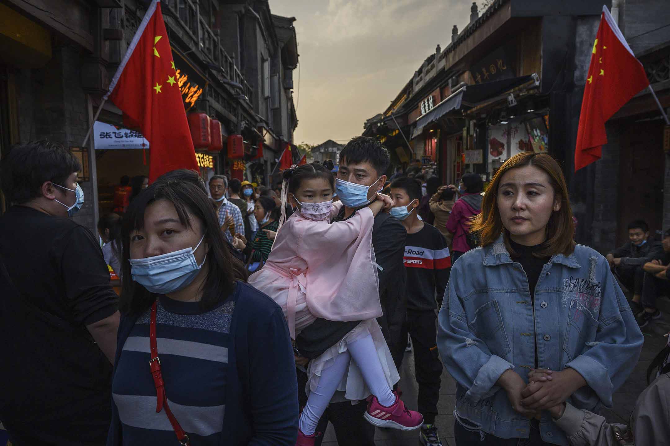 2020年10月3日中國北京,黃金周假期期間,一名中國男子帶著身著傳統服裝的女兒在旅遊區散步。