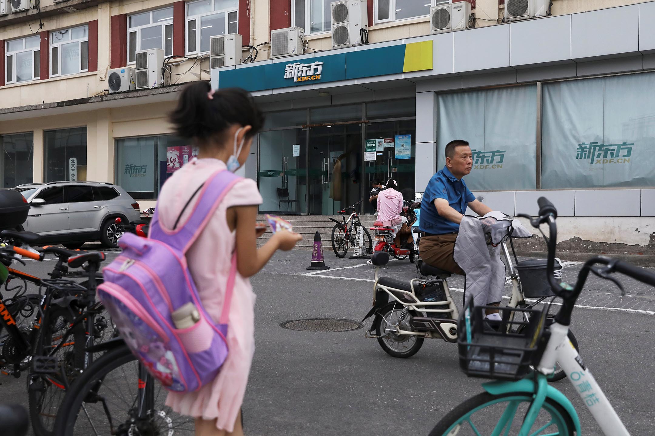 2021年7月26日中國北京,一名背著書包的女孩站在新東方教育科技集團的一家店附近。
