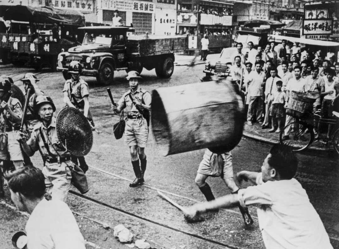 1967年6月,六七暴动期间,一名男子在街头向警察扔垃圾桶。