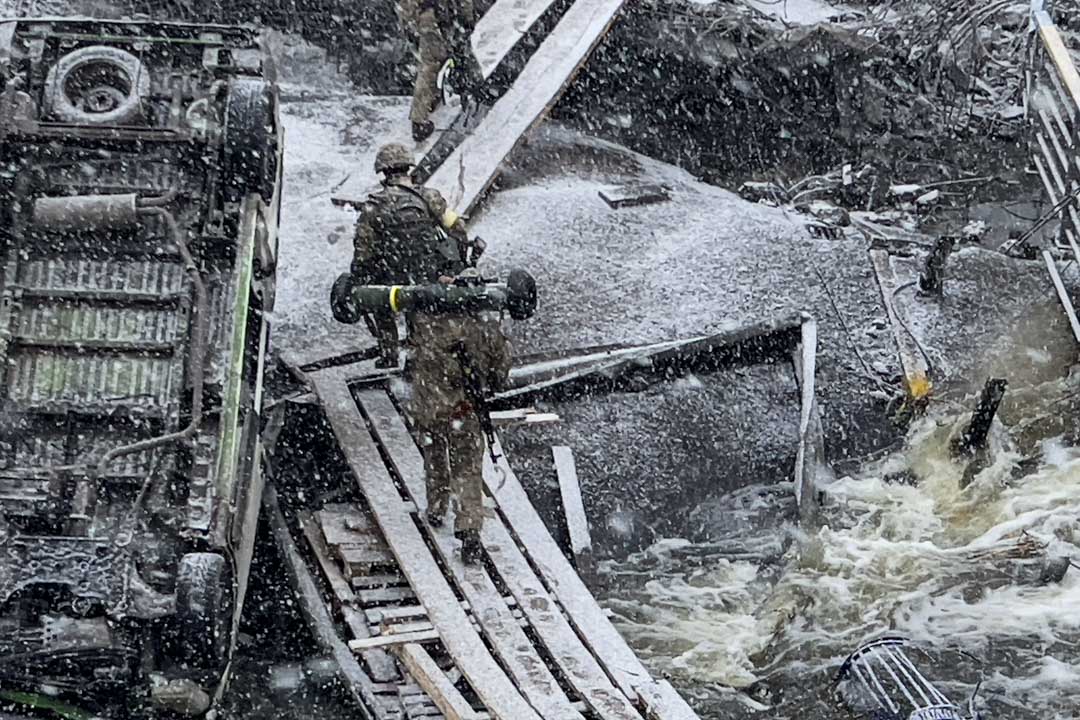 2022年3月9日,乌克兰首都基辅西部城市伊尔平(Irpin),数名乌克兰士兵在雪中走过一条河道。
