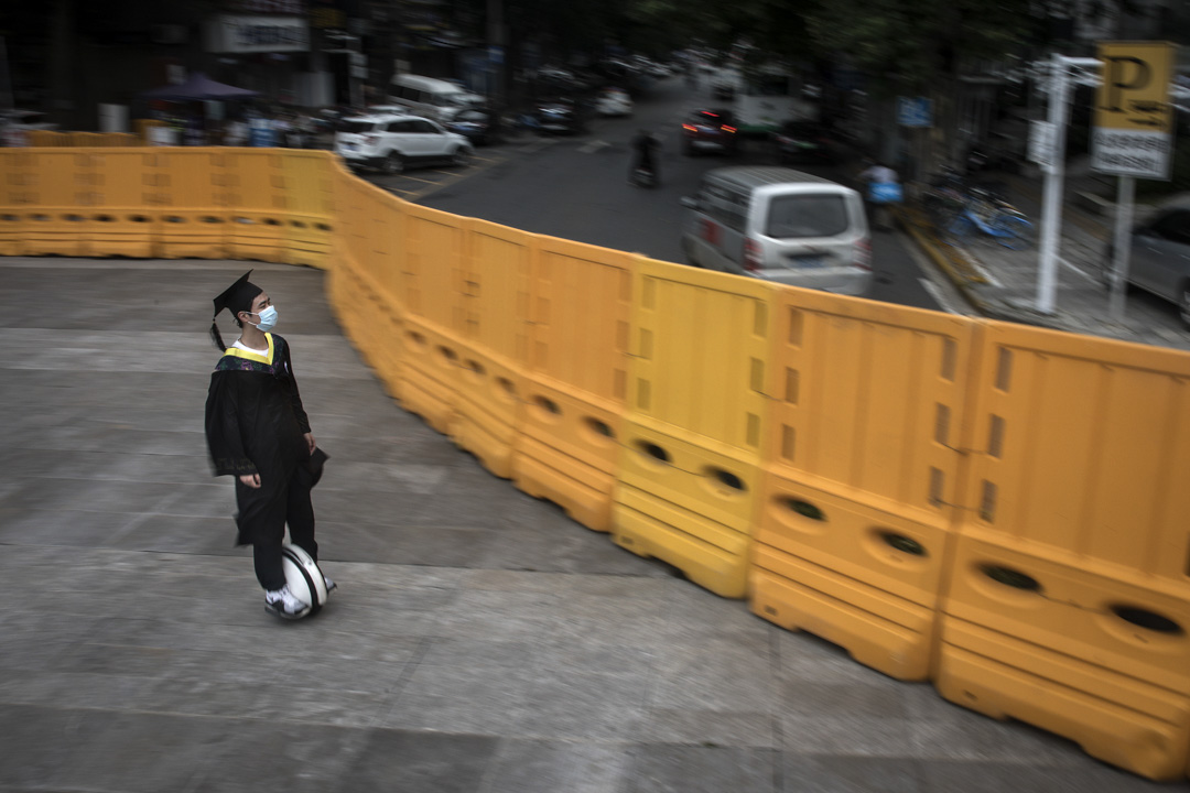 2020年6月11日，武漢大學畢業生戴口罩騎平衡車經過臨時圍牆，打算進出校園。