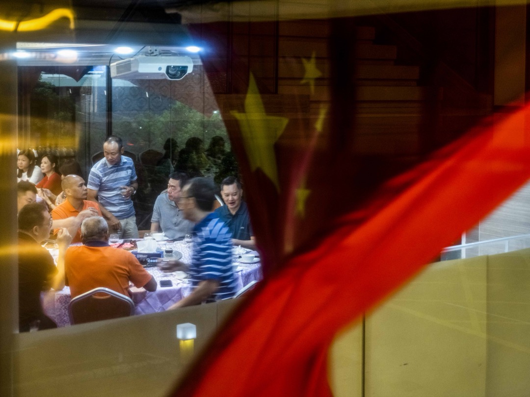 2022年6月26日,食客在尖东一间酒楼晚宴,窗外有一幅国旗在风中飘扬。摄:林振东/端传媒