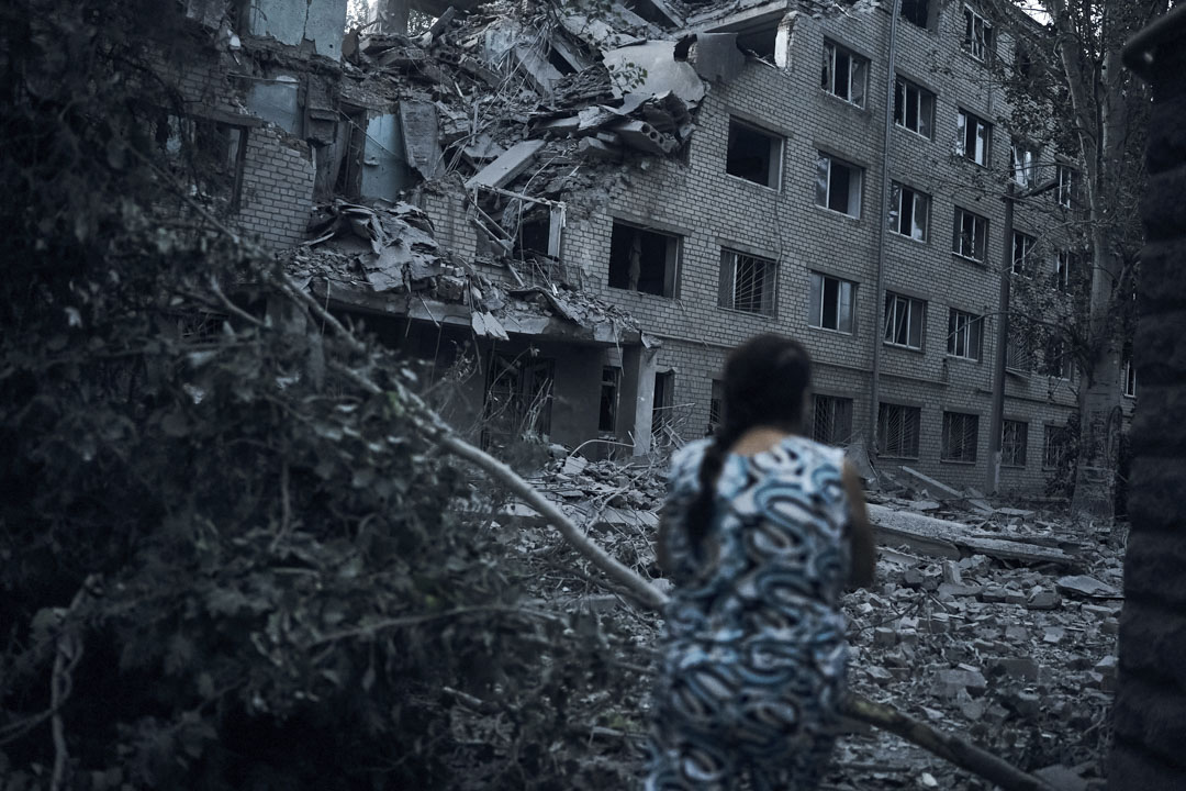 2022年8月2日,乌克兰 Mykolaiv 发生夜间砲击后,一名妇女走在住宅楼的废墟中。
