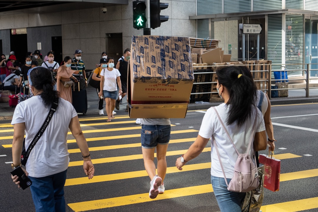 香港,一名移工抬著一个纸箱过马路。