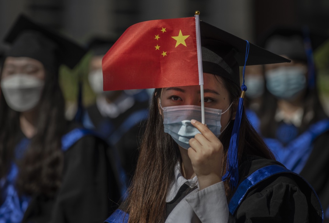 2020年6月30日,中国北京,中国人民大学举行毕业礼,一名毕业生用国旗遮挡太阳。