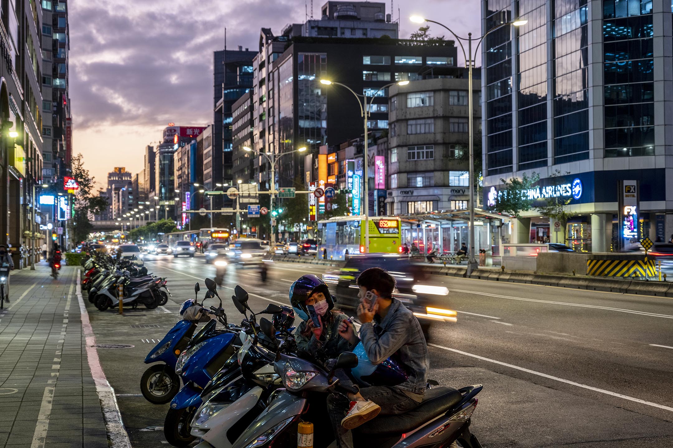 2022年11月19日,台北,年青人坐在機車上聊天。