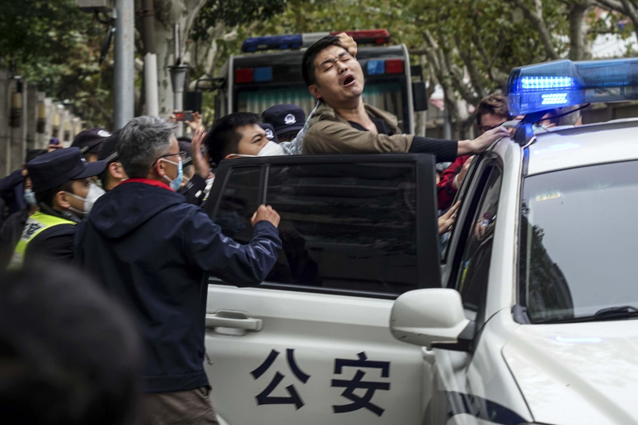 2022年11月27日,上海的示威现场,一名示威者被警察逮捕并被押上警车。