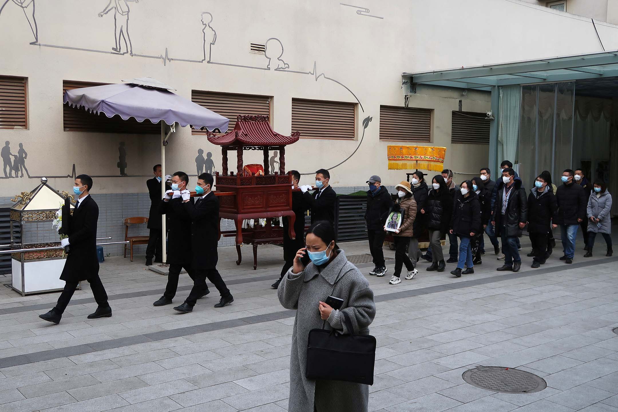 2022年12月28日,四川省成都,工作人员在火葬场外带著骨灰盒参加送葬队伍。