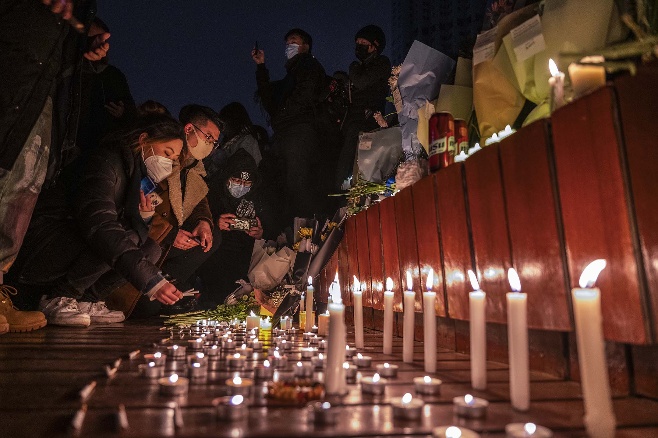 2022年11月27日,北京,为悼念乌鲁木齐大火死难者,市民在追悼期间点燃蜡烛。
