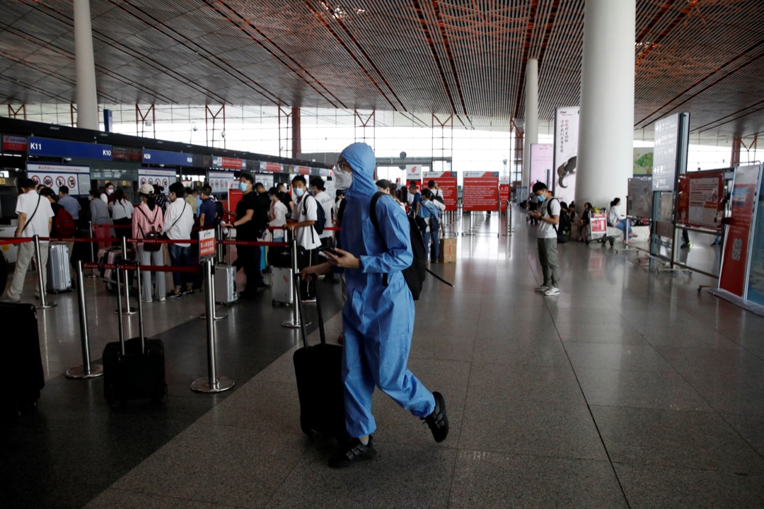 2020年6月17日,中國北京首都機場,一名穿保護衣的旅客在機場大堂走過。