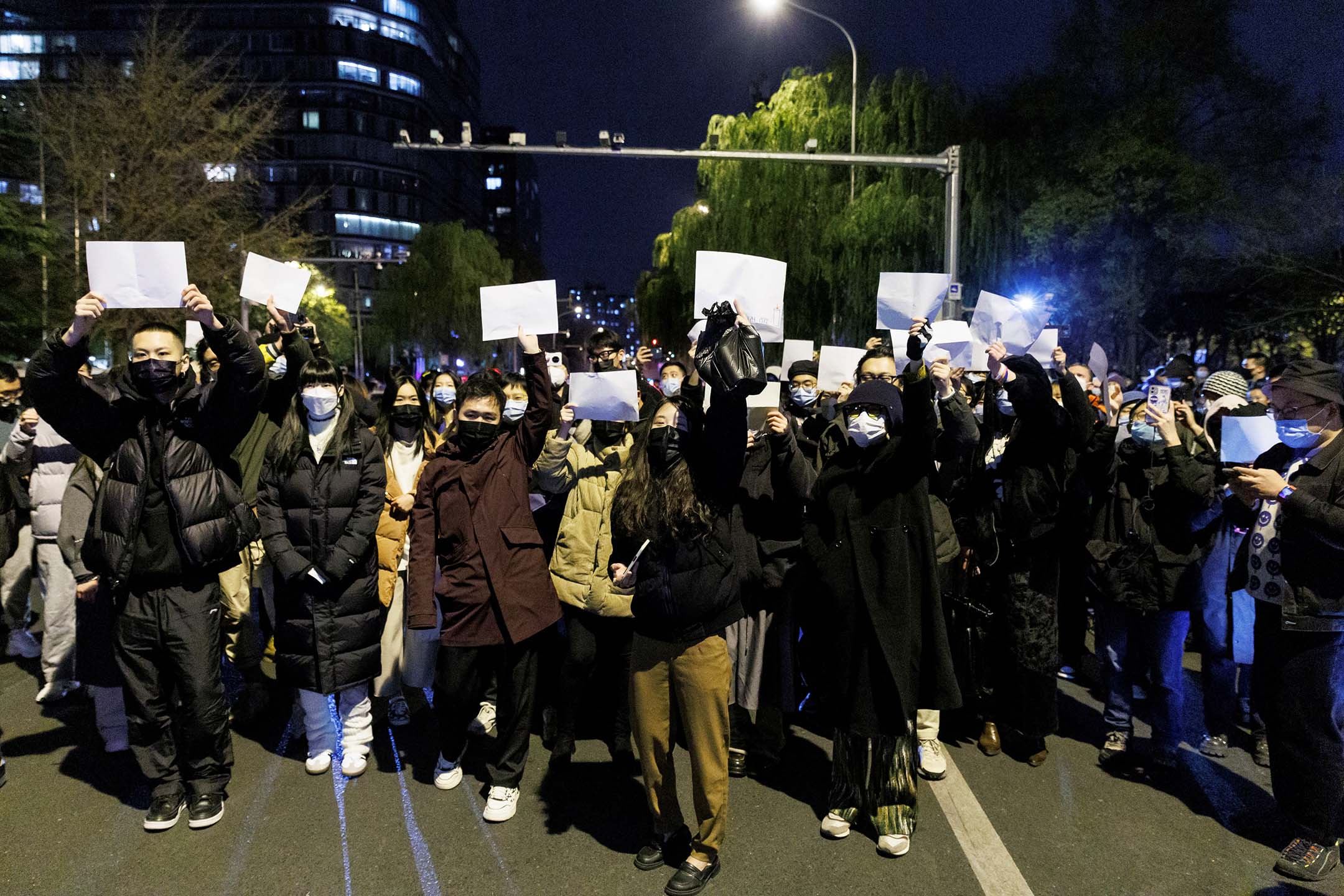 2022年11月27日,北京,烏魯木齊火災遇難者紀念活動期間,人們聚集在一起守夜並舉著白紙抗議。