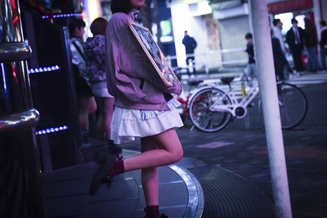 日本東京新宿區,一名女子在街上手持酒吧的廣告牌宣傳。