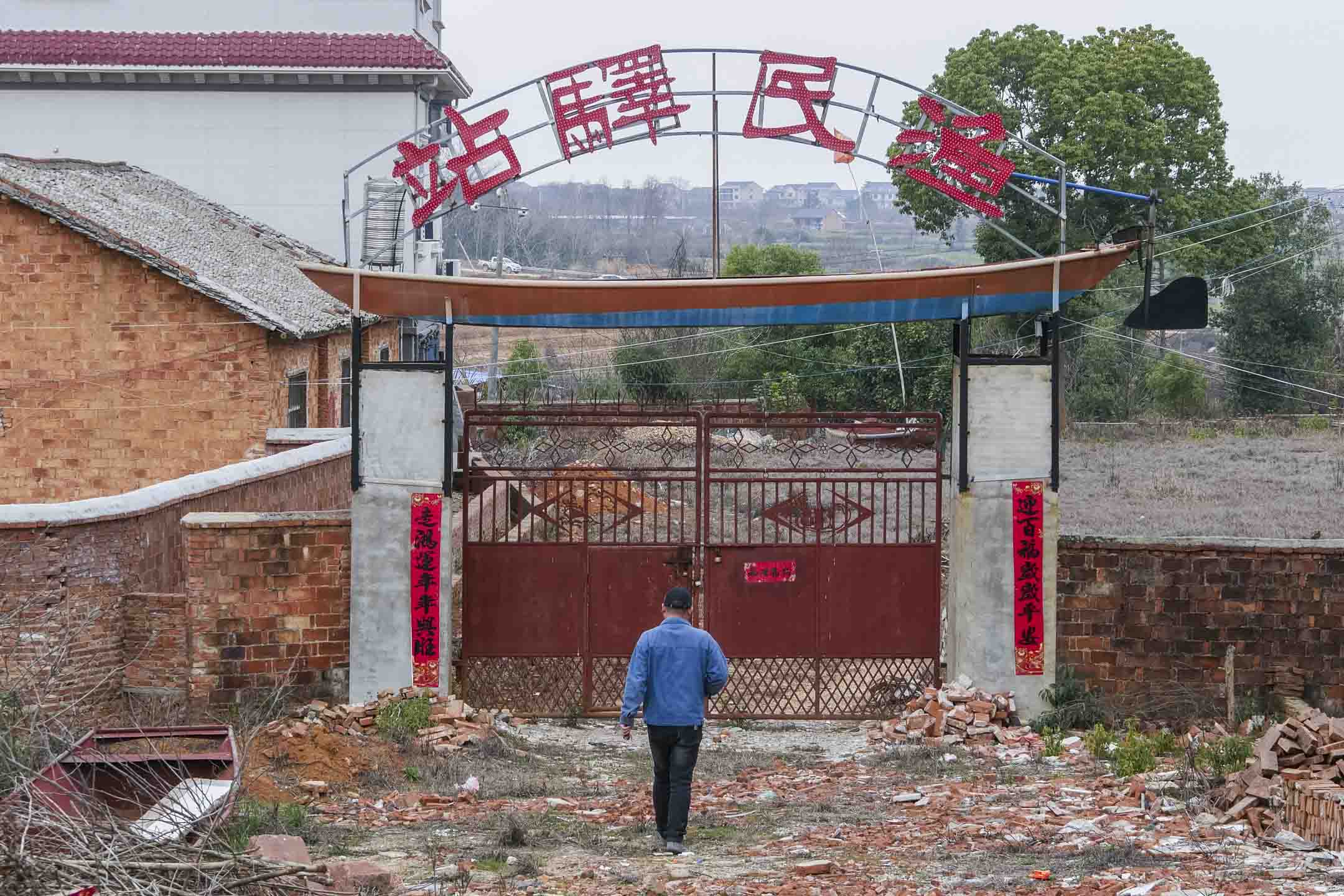 朱景園站在「漁民驛站」大門前,門頭是一艇從漁民手中收來的舊船。攝影:Anita Zhang