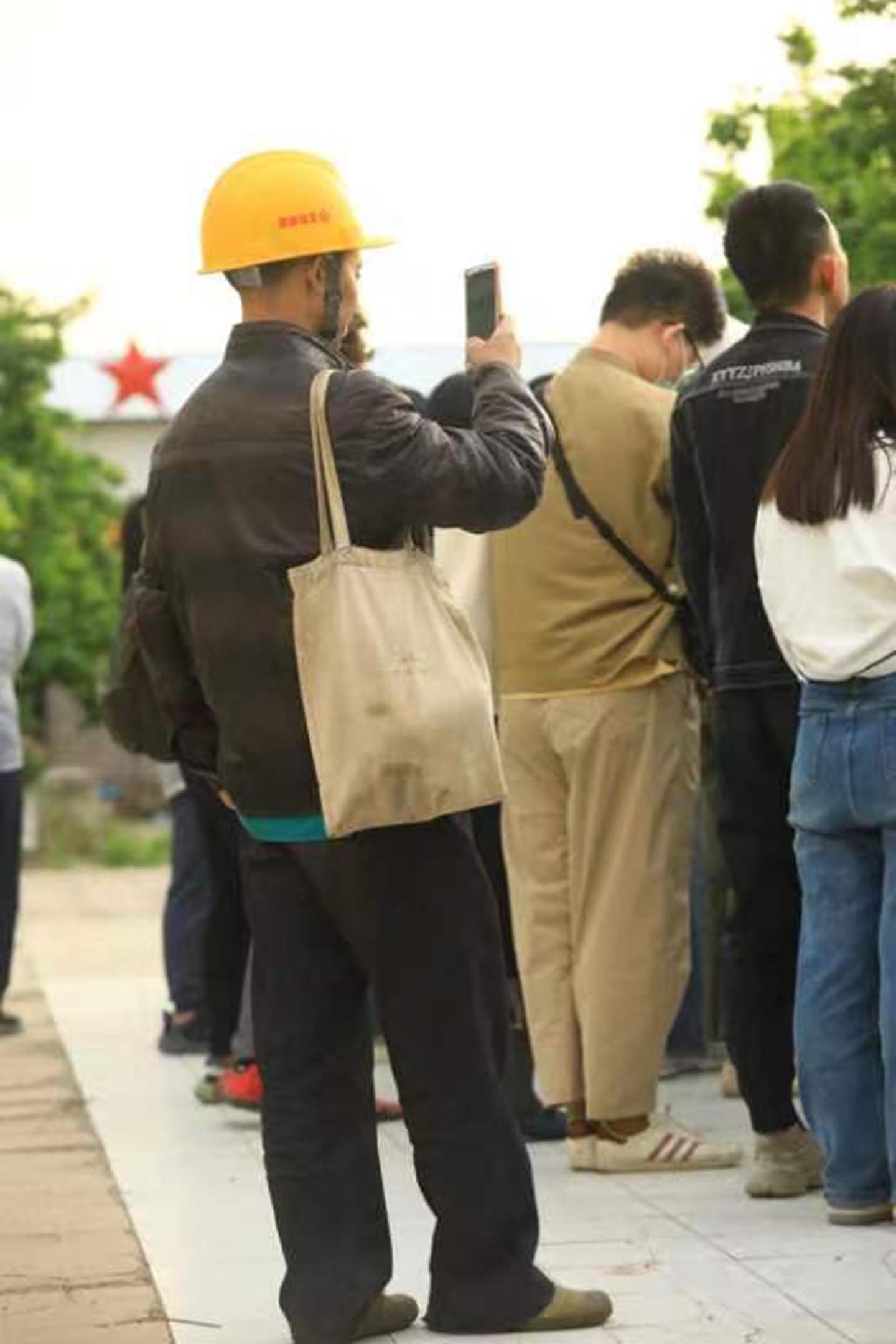 一个工人在用手机拍摄告别式。摄影:网友“冲绳流浪猫”
