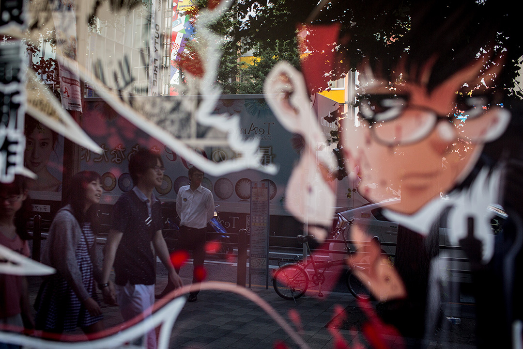 2014年6月19日,日本東京,一間書店的櫥窗裡映出一對情侶的影子。攝:Chris McGrath/Getty Images