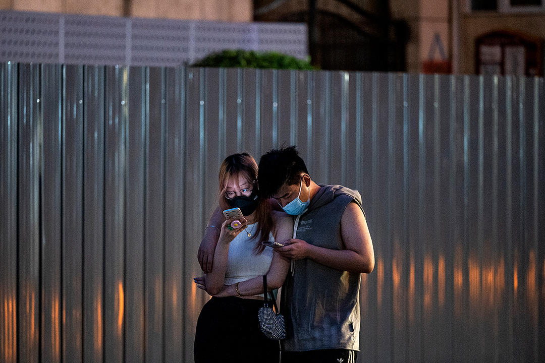 北京街上一雙觀看手機的情侶。攝:Kevin Frayer/Getty Images