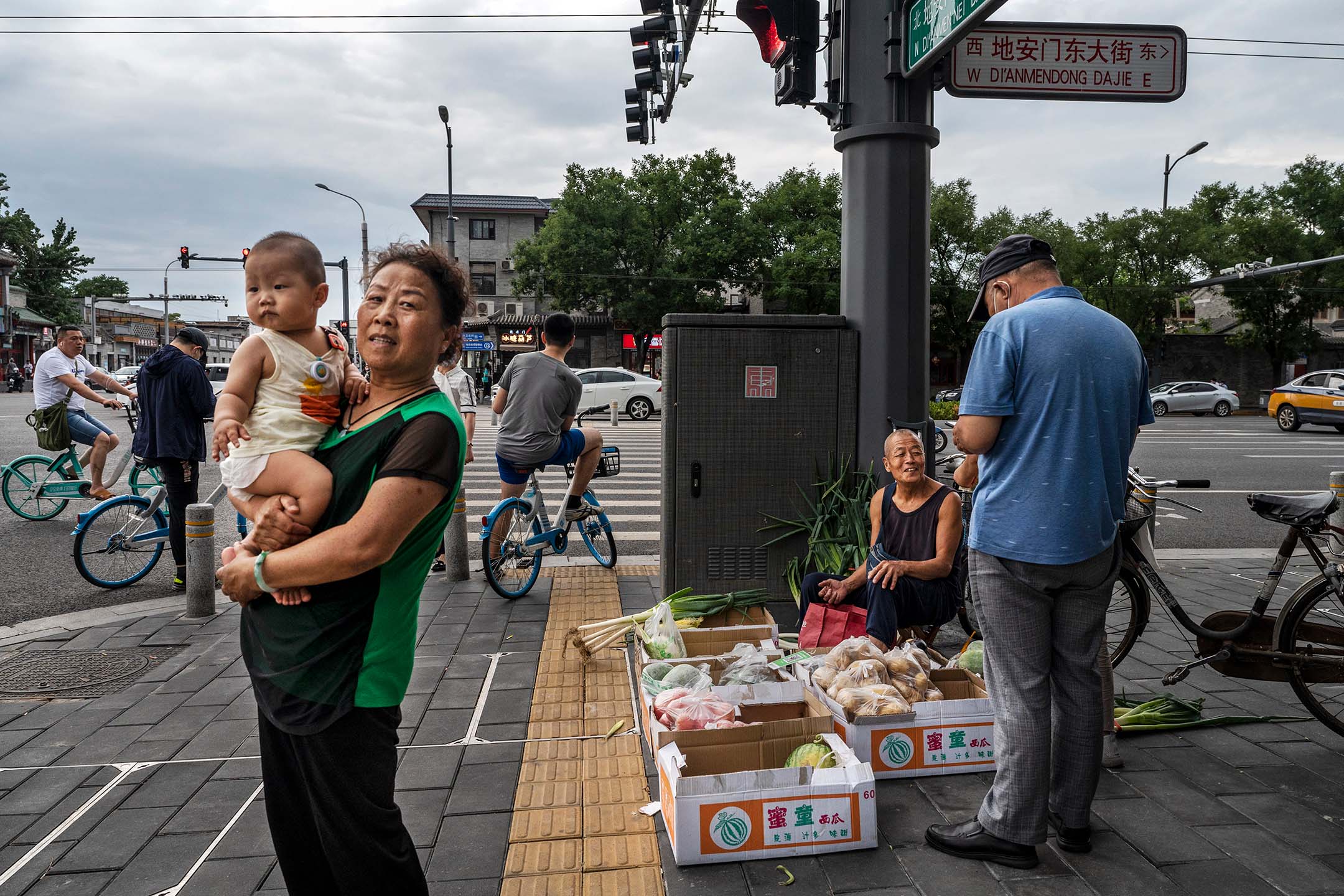 2022年6月28日,中國北京, 一名女子站在街頭上抱著孩子。攝:Kevin Frayer/Getty Images