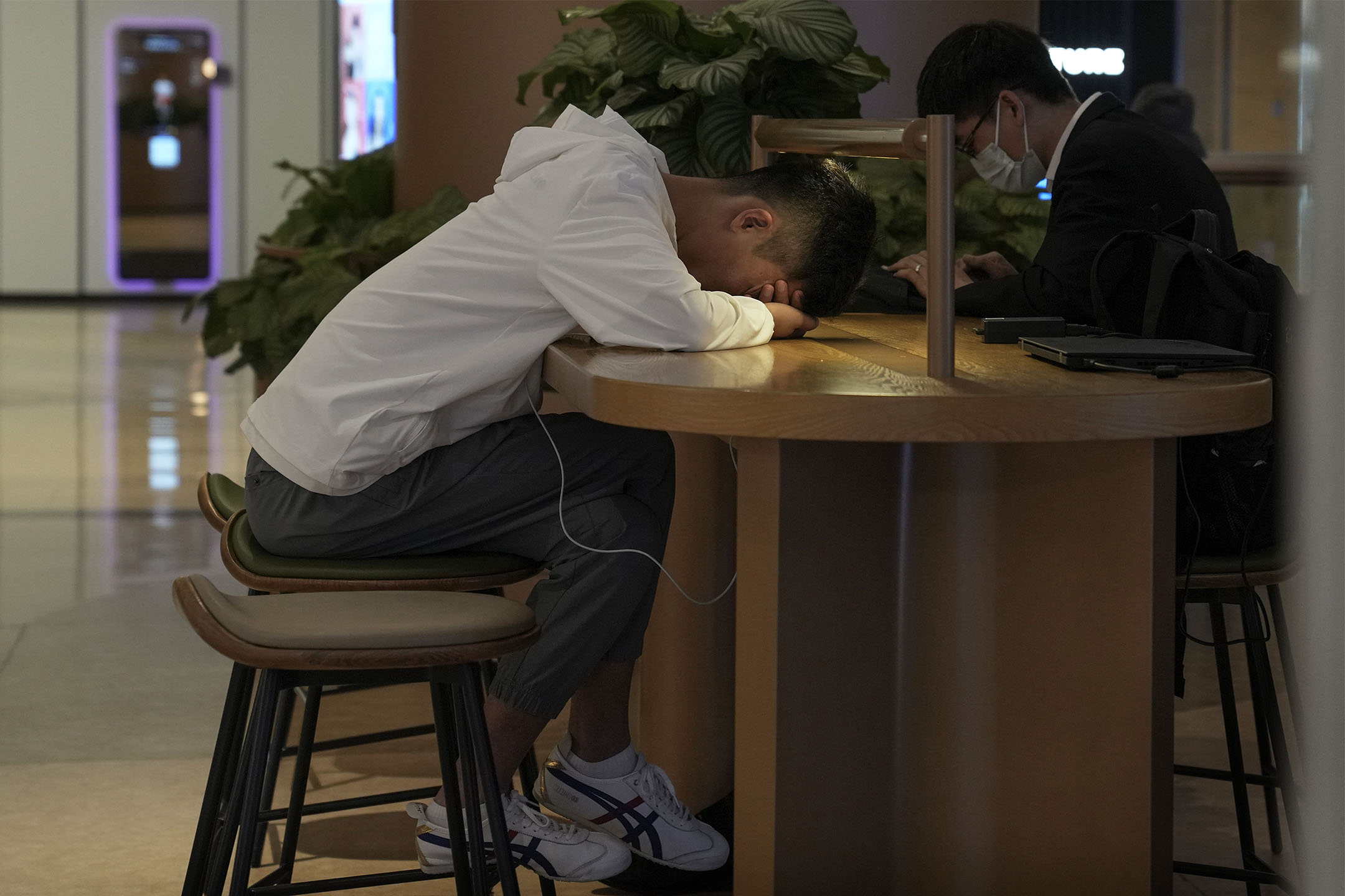 2023年5月24日,北京一家购物中心内的咖啡馆,一名男子在小憩。摄:Andy Wong/AP/达志影像