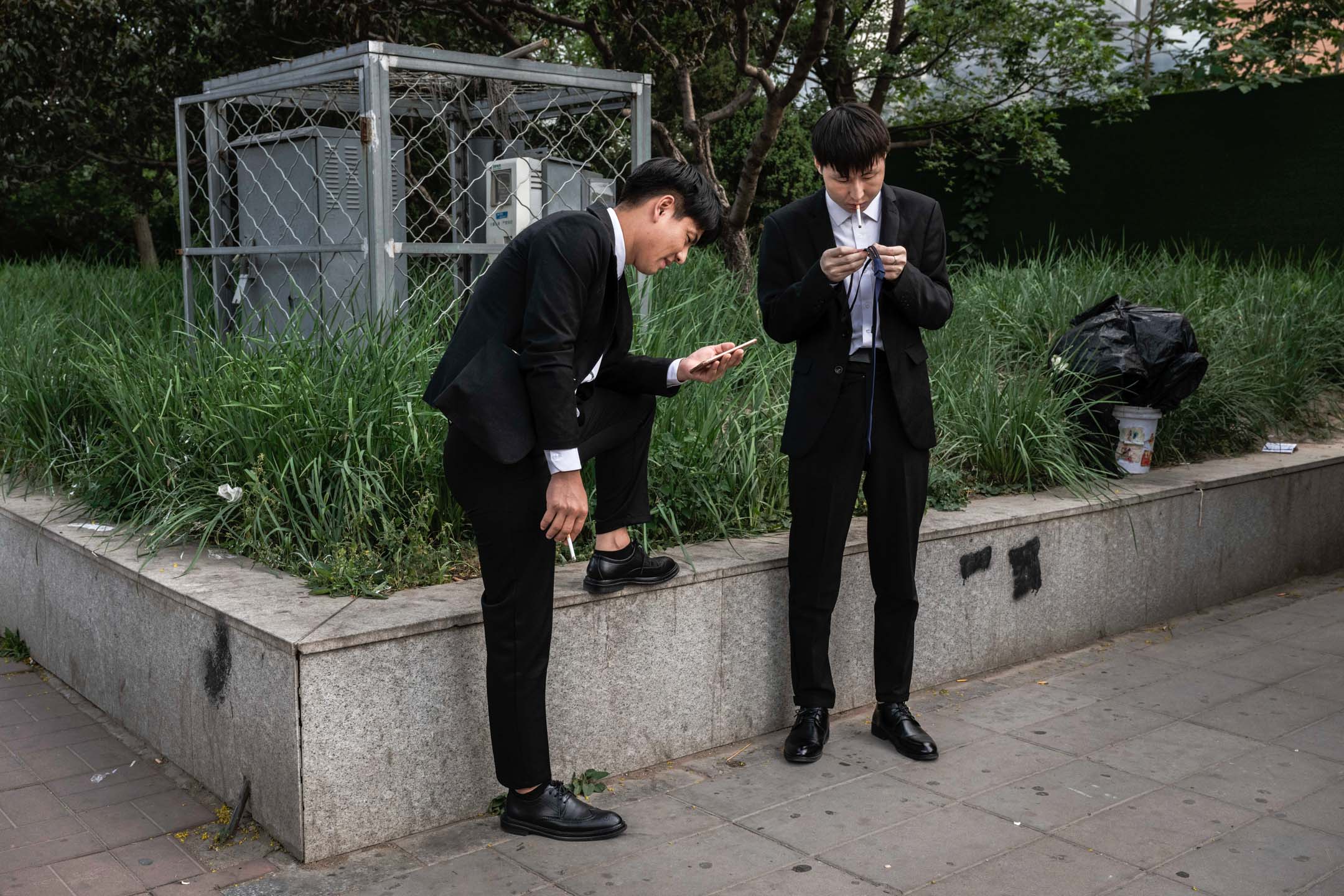 2023年6月7日,中国北京,两名男子站在地铁站外等候。摄:Kevin Frayer/Getty Images