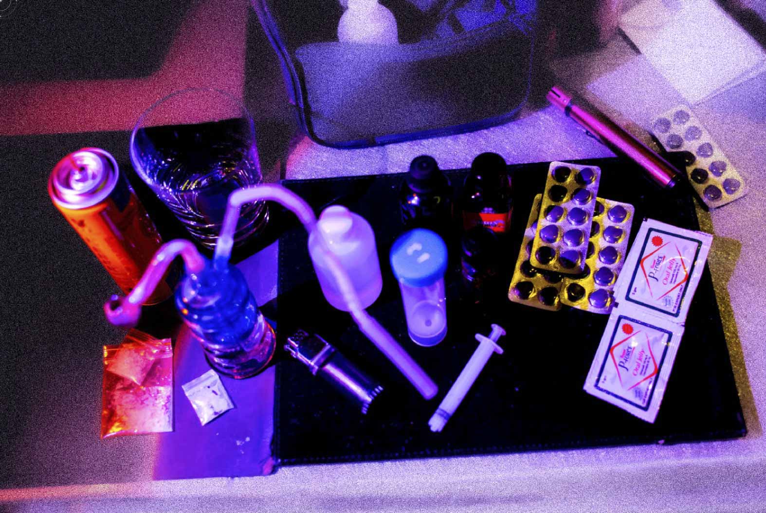 左下角是冰,使用冰壶需要点火,旁边有汽油罐及火机。正中间是 G 水,需要时先用针筒量度份量放入杯中,然后混合少量称为 mixer 的饮料(例如 Monster Energy 或可乐等)才能饮用。右边是液体伟哥(Viagra,威而钢)、Poppers 以及啫喱伟哥。摄:林振东/端传媒