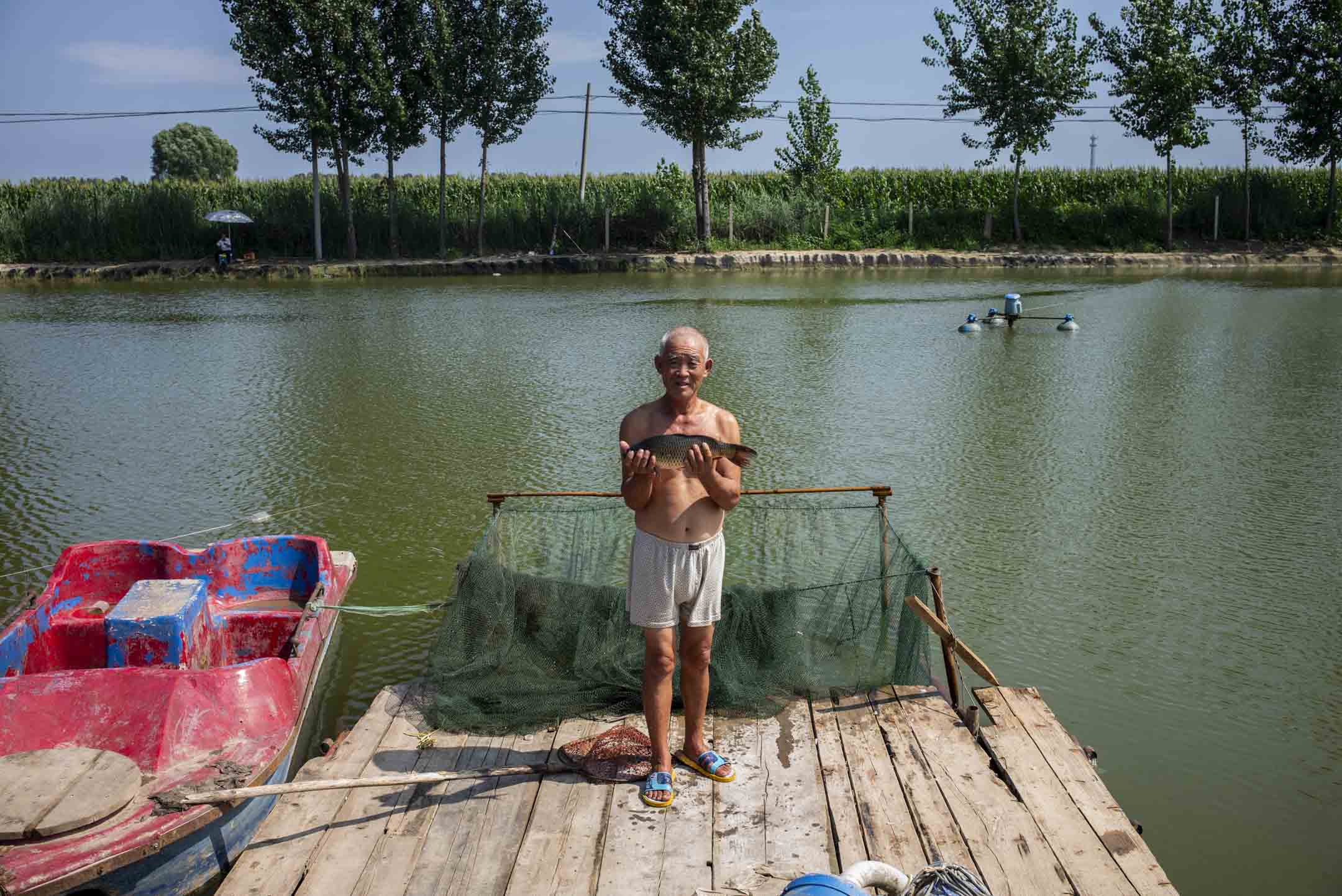 2018年,安新白洋淀的漁民手捧一條魚。攝:林文清/端傳媒