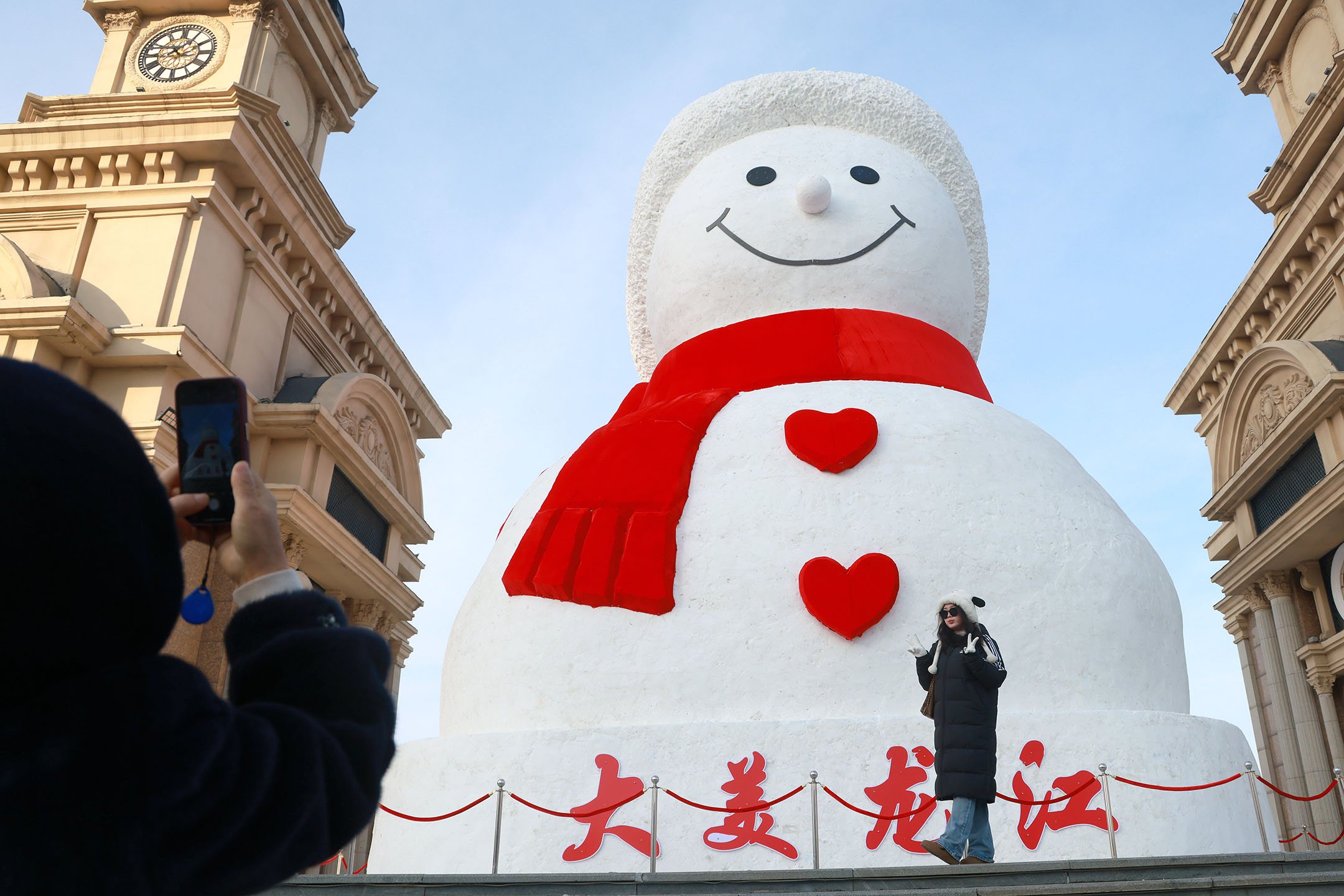2023年12月15日,中国黑龙江省哈尔滨市,游客在哈尔滨音乐公园参观18公尺高的雪人。摄:VCG/VCG via Getty Images