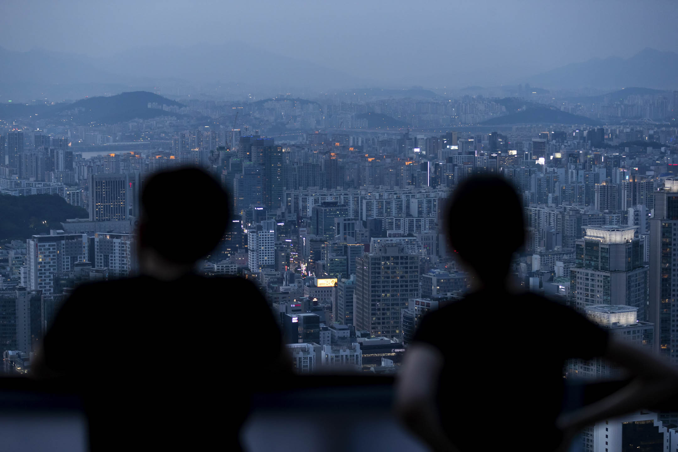 2020年7月9日,韩国首尔黄昏时分,人们眺望城市天际线。摄:SeongJoon Cho/Bloomberg via Getty Images