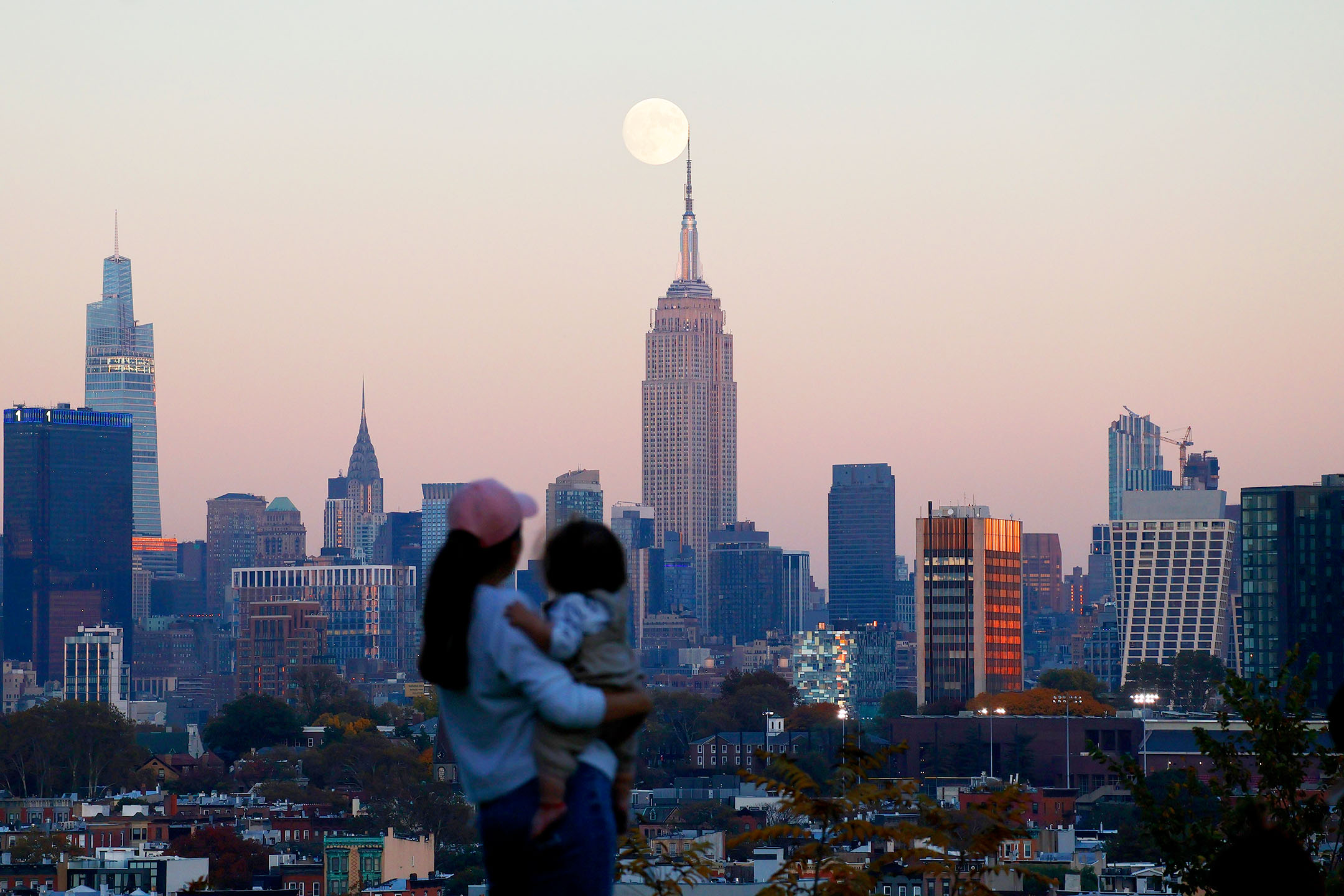 2023年10月27日,美國紐約,一名婦女看著月亮在城市後升起。攝:Gary Hershorn/Getty Images