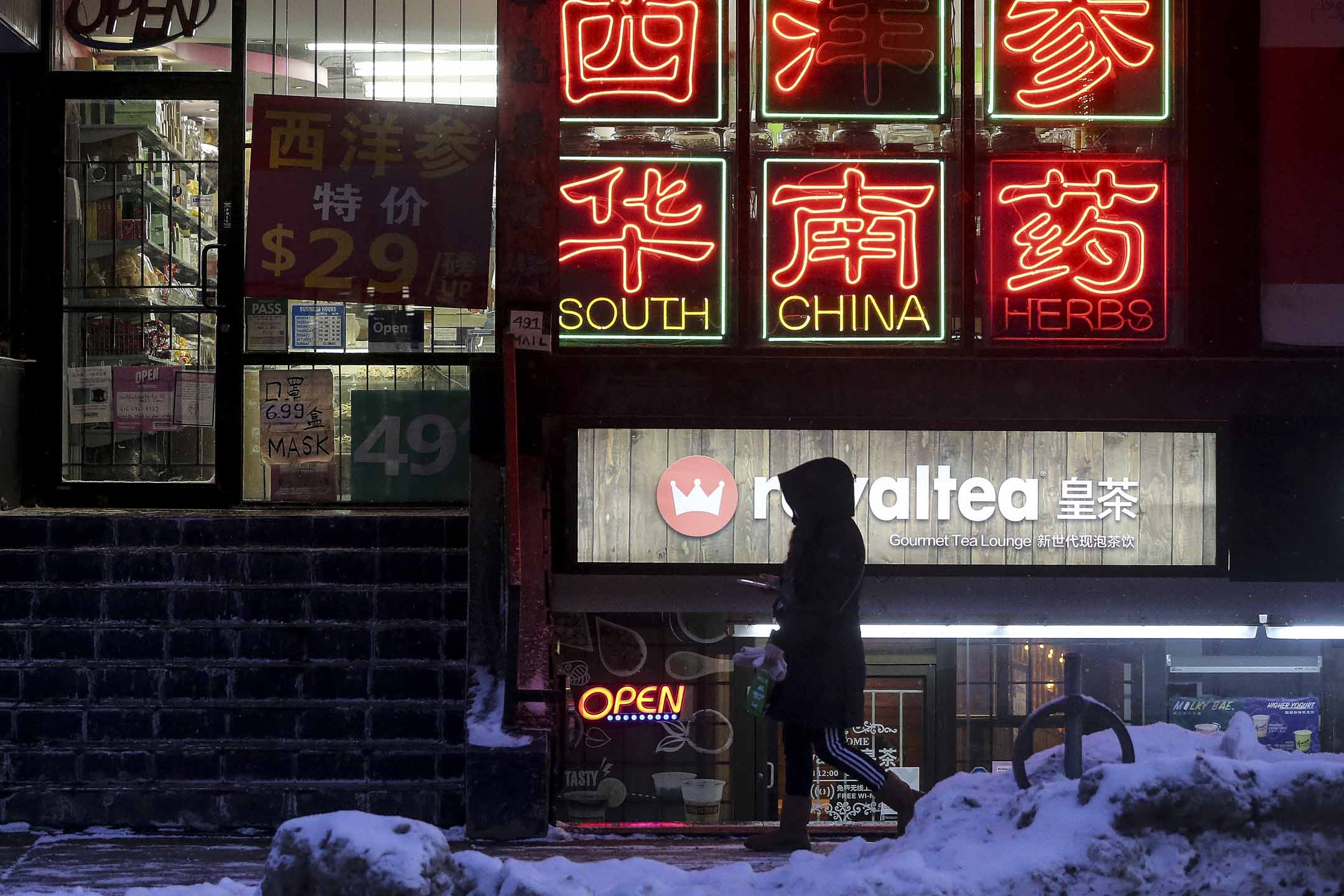多伦多唐人街晚上一位女士在商店前经过。摄:Steve Russell/Toronto Star via Getty Images