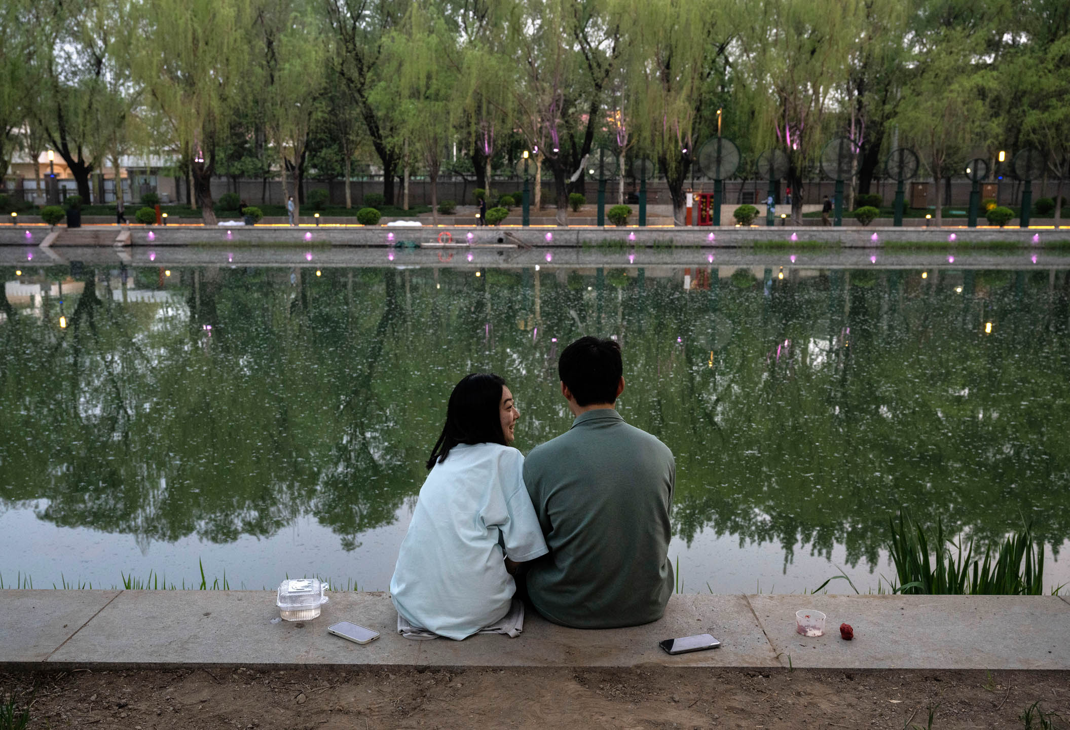2024年4月12日,中國北京,一對情侶坐在河邊釣魚。攝:Kevin Frayer/Getty Images