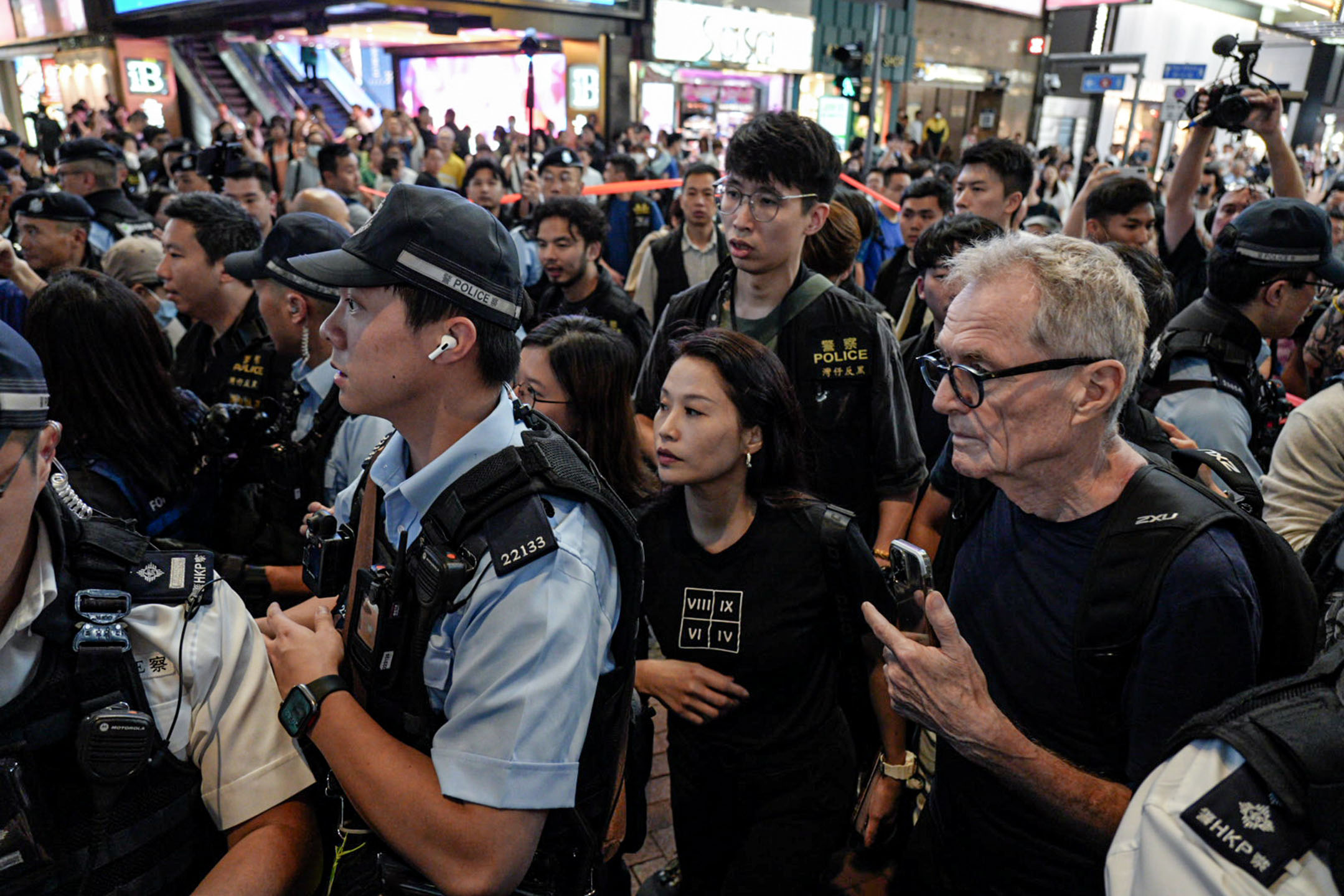 2024年6月4日,一名女士身穿印有罗马数字的衣服,被警方包围后带上警车。摄:Ryan Lai/端传媒