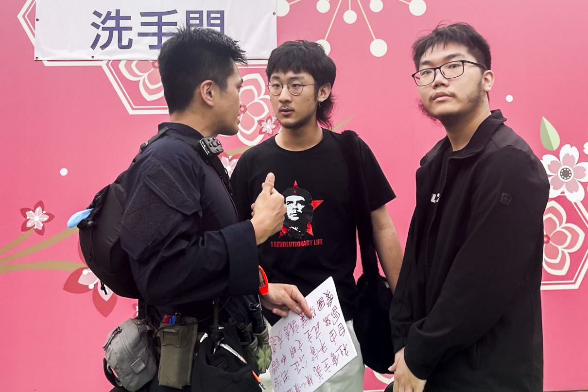 2024年6月4日,维园家乡情市集,有两名男子手持写上“社会主义核心价值观”等字眼的标语。其中一名男子被在场保安包围抬离维园,警察将他带上警车。