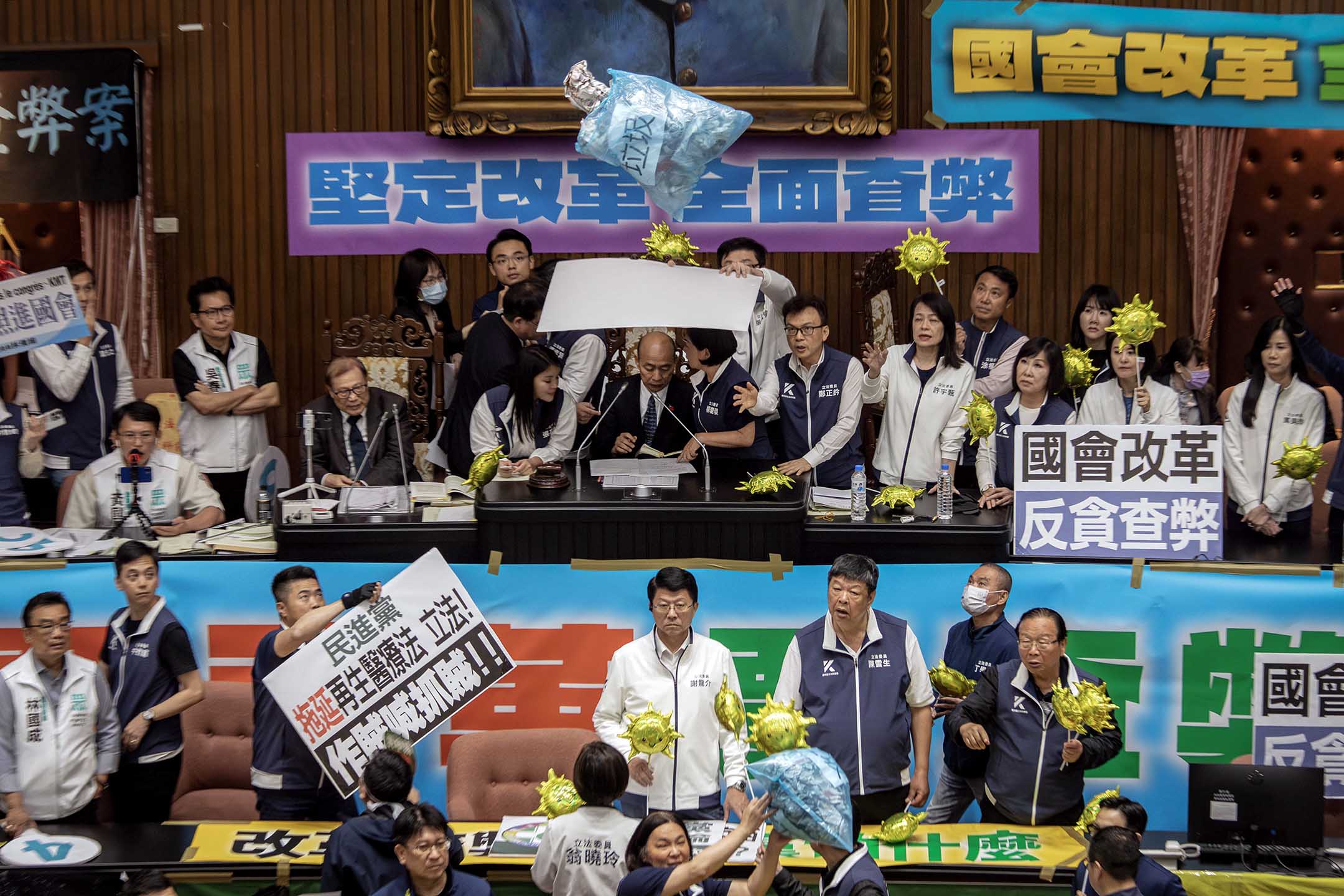 2024年5月28日，台北，立法院進行國會改革法案審議，立法院内民進黨立委向主席台掉垃圾，國民黨立委用看板阻擋保護立法院長韓國瑜。攝：陳焯煇/端傳媒