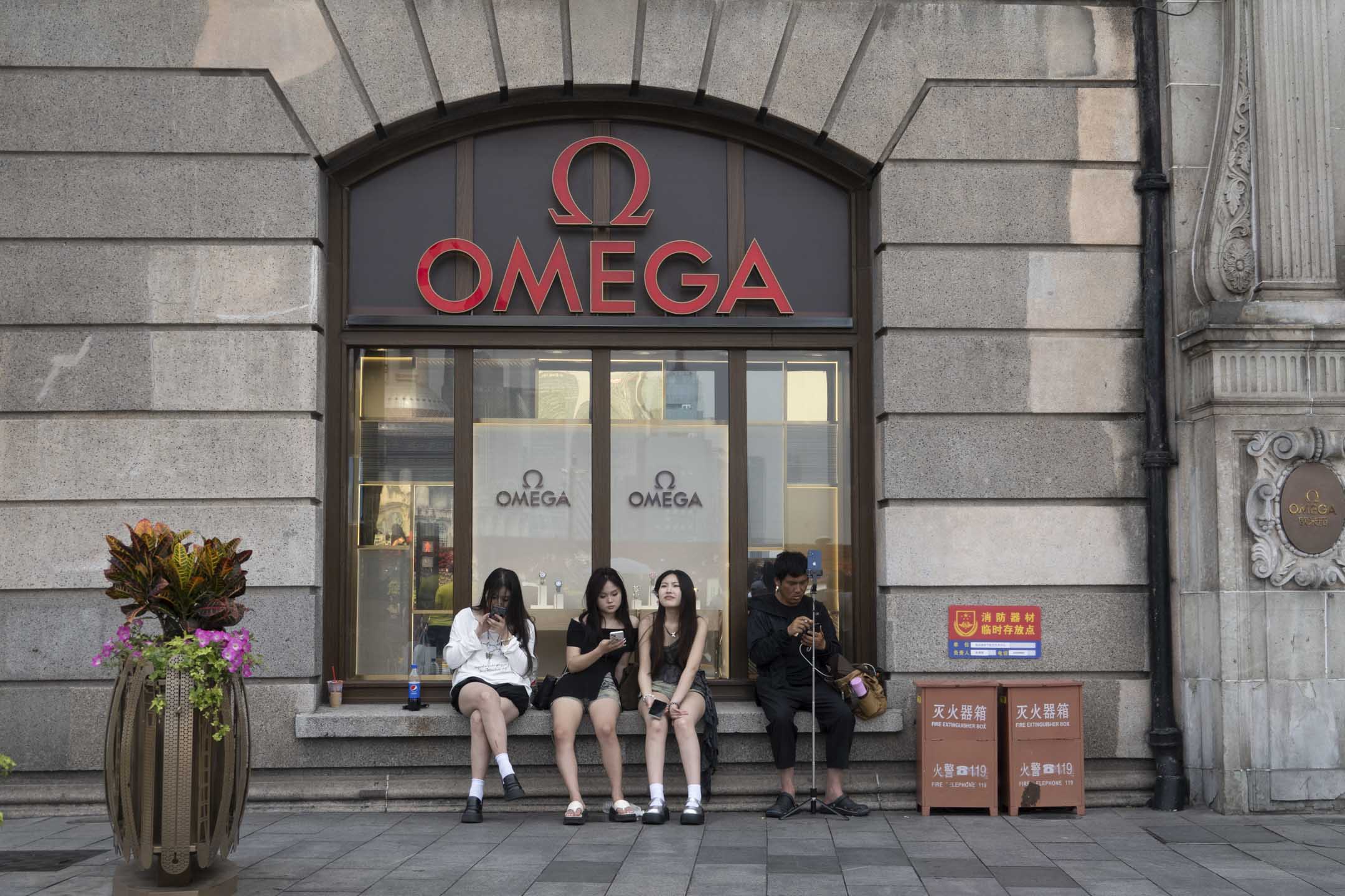 2024年6月4日,中國上海,遊客坐在的 OMEGA 手錶店前。攝:Costfoto/NurPhoto via Getty Images